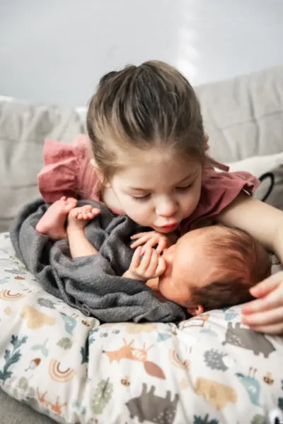 Sister Kissing Newborn Brother Photo